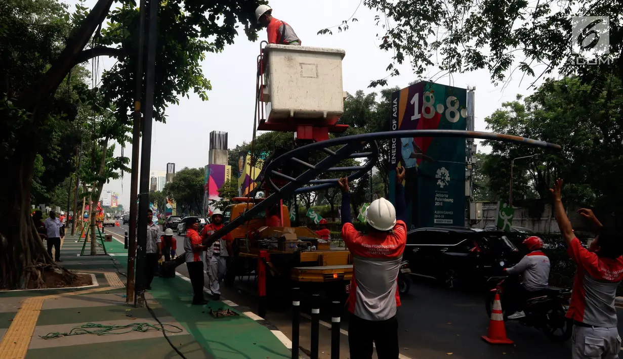 Petugas membawa lampu penerangan jalan di trotoar Jalan Asia Afrika dan Gelora, Jakarta, Rabu (1/8). Pembuatan jalur sepeda ini sempat menuai protes akibat tiang listrik dan lampu jalan menghalangi, sehingga menyulitkan pesepeda. (Liputan6.com/JohanTallo)