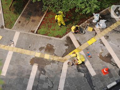 Pasukan Kuning dari Dinas Bina Marga memperbaiki garis kuning di trotoar kawasan Tanah Abang, Jakarta, Sabtu (22/5/2021). Garis kuning di trotoar yang dibuat khusus untuk jalur penyandang tunanetra tersebut diperbaiki agar nantinya dapat dilintasi dengan aman dan nyaman. (Liputan6.com/Angga Yuniar)
