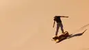 Seorang turis mencoba atraksi berseluncur dengan sandboarding di gurun Dubai pada 11 Januari 2021. Di sini para wisatawan dapat mencoba sensasi bermain sandboarding sambil memandang hamparan lautan pasir cokelat. (Photo by GIUSEPPE CACACE / AFP)