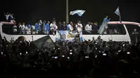 Lionel Messi dan empat rekannya duduk di atap belakang bus terbuka pada parade begitu tiba di kampung halaman. Mereka diarak usai membawa Argentina juara Piala Dunia 2022. (AFP/Luis Robayo)