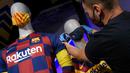 Penjaga toko memasang masker berlogo Barcelona ke Manekin di Toko Asesoris Barcelona, Senin (25/5/2020). Di tengah pandemi virus Corona, Barcelona menjual masker dengan harga 18 euro atau sekitar Rp 291 ribu. (AFP/Lluis Gene)