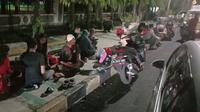 Sejumlah pemudik Lebaran 2022 terpaksa makan sahur di trotoar lantaran jalan arteri di Kota Cilegon, Banten menuju Pelabuhan Merak macet panjang sejauh 10 km, Jumat (29/4/2022). (Liputan6.com/Yandhi Deslatama)
