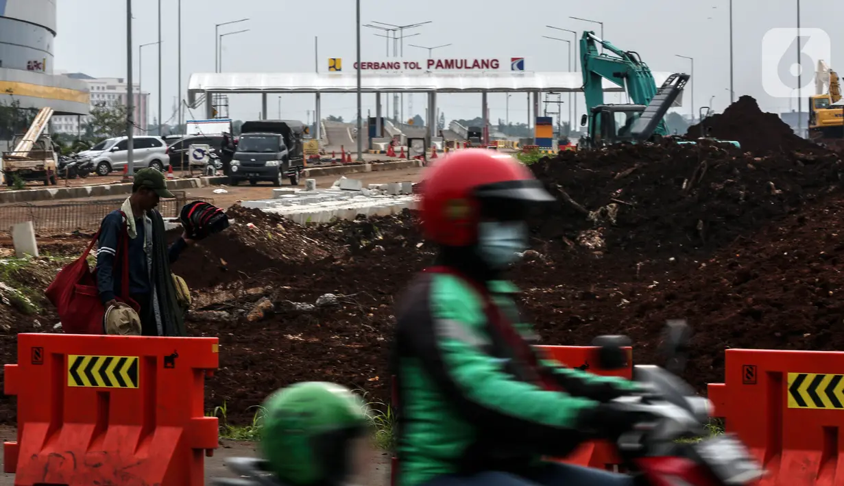 Pengendara motor melintas di depan pembangunan pintu Tol Pamulang di Tangerang Selatan, Banten, (17/2/2021). Jalan Tol Serpong-Cinere ini merupakan bagian dari jaringan Jalan Tol JORR II sepanjang 10,14 kilometer. (Liputan6.com/Johan Tallo)