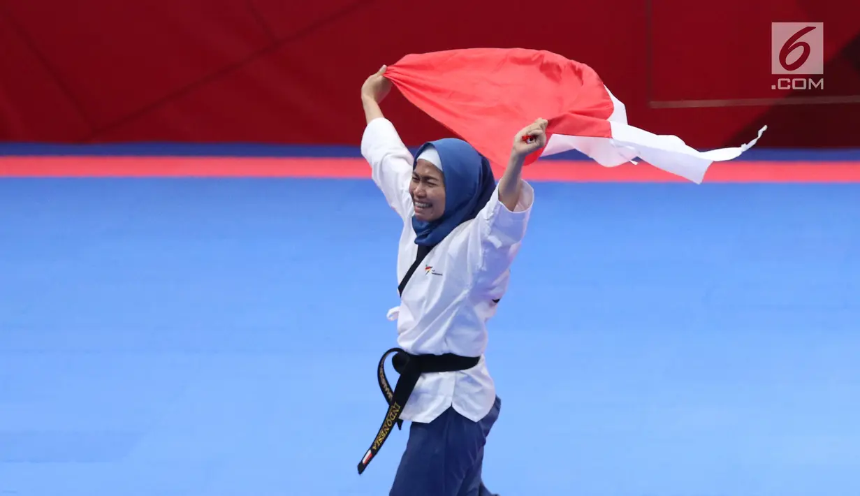 Atlet Taekwondo putri Indonesia, Defia Rosmaniar mengibarkan bendera Merah Putih saat merayakan kemenangan atas Salahshouri Marjan (Iran) pada Final Women Individual Poomsae di JCC, Jakarta, Minggu (19/8). (Liputan6.com/Helmi Fithriansyah)