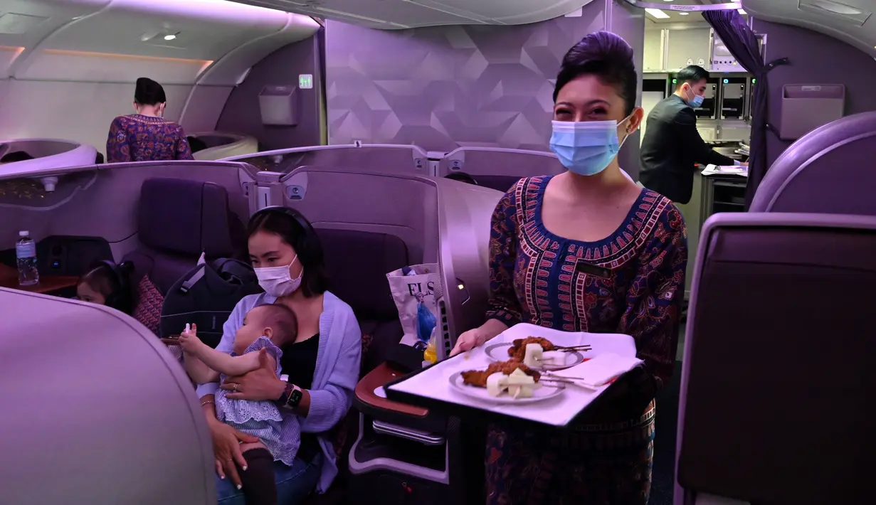 Pramugari Singapore Airlines menyajikan makanan di kelas bisnis saat makan siang perdana di Restaurant A380 @Changi di pesawat Airbus A380, di Bandara Internasional Changi, 24 Oktober 2020. Maskapai penerbangan ini mengubah salah satu pesawatnya menjadi sebuah restoran mewah. (ROSLAN RAHMAN/AFP)