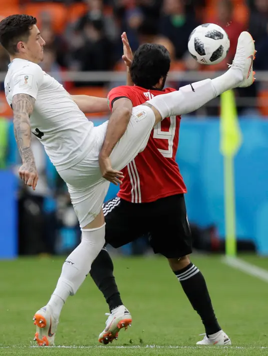 Pemain Uruguay Jose Gimenez berebut bola dengan pemain Mesir Marwan Mohsen saat bertanding pada grup A Piala Dunia 2018 di Yekaterinburg Arena, Rusia, (15/6). Uruguay menang dramatis atas Mesir 1-0. (AP Photo / Mark Baker)
