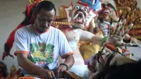 Seorang seniman memasangkan rambut saat menyelesaikan pembuatan patung atau yang dikenal ogoh-ogoh sebelum Perayaan Nyepi di Denpasar, Bali (12/3). Perayaan Nyepi akan jatuh apada tanggal 17 Maret 2017. (AFP Photo/Sonny Tumbelaka)
