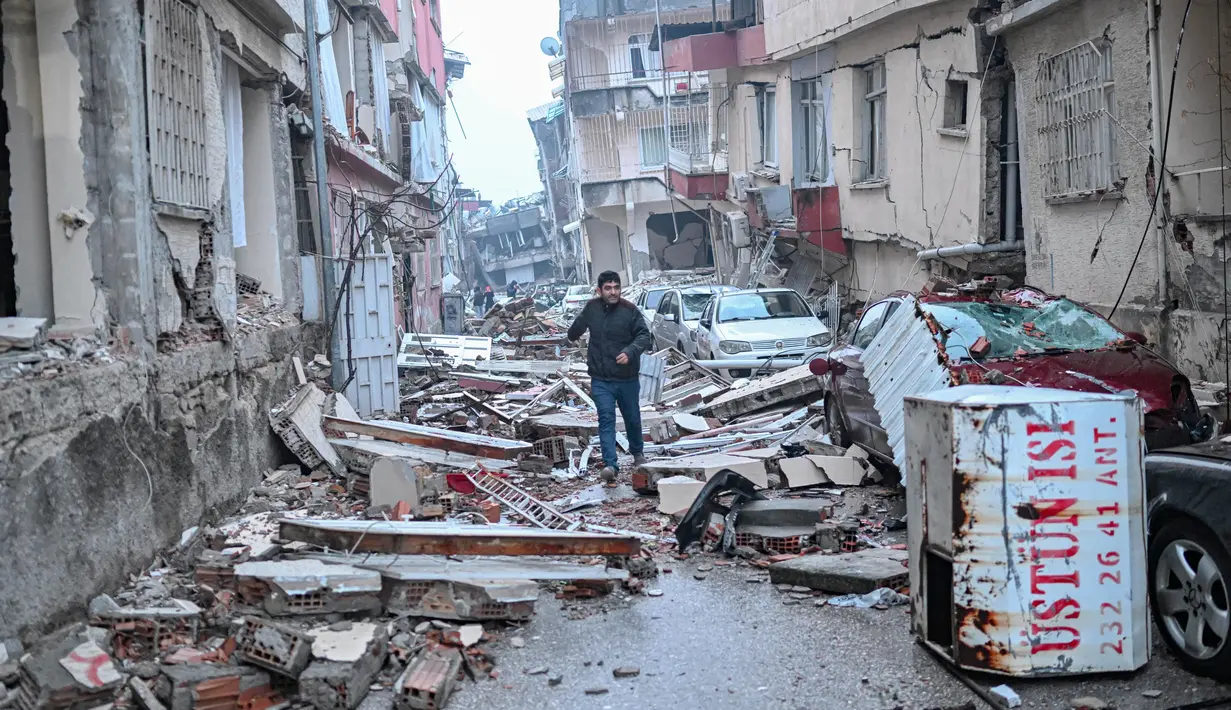 <p>Seorang pria berlari di sepanjang jalan yang dipenuhi puing-puing, di Hatay, sehari setelah gempa berkekuatan 7,8 magnitudo melanda Turki, Selasa (7/2/2023). Tim penyelamat di Turki dan Suriah menghadapi cuaca dingin, gempa susulan, dan bangunan yang runtuh, saat mereka menggali untuk para penyintas yang terkubur oleh gempa bumi yang menewaskan lebih dari 5.000 orang. (BULENT KILIC / AFP)</p>