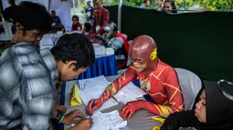 Petugas Kelompok Penyelenggara Pemungutan Suara (KPPS) berkostum superhero The Flash mendata warga yang akan mencoblos dalam Pemilu 2019 di sebuah TPS di Surabaya, Jawa Timur, Rabu (17/4). Ada sembilan petugas KPPS yang mengenakan kostum superhero di TPS ini. (Juni Kriswanto/AFP)