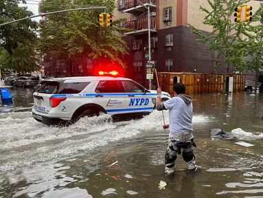 Seorang pria bekerja membersihkan saluran air akibat banjir di wilayah Brooklyn, New York, Amerika Serikat, Jumat (29/9/2023). Hujan badai yang dahsyat pada jam-jam sibuk telah melanda wilayah metropolitan New York. (AP Photo/Jake Offenhartz)