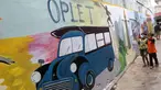 Anak-anak melintas di depan mural bertema budaya Betawi di kawasan Kampung Sentra Kreatif, RW 006 Kota Bambu Selatan, Jakarta, Rabu (3/11/2021). Pengembangan kawasan perkampungan ini bertujuan untuk mengunggah semangat masyarakat agar melestarikan budaya. (Liputan6.com/Herman Zakharia)