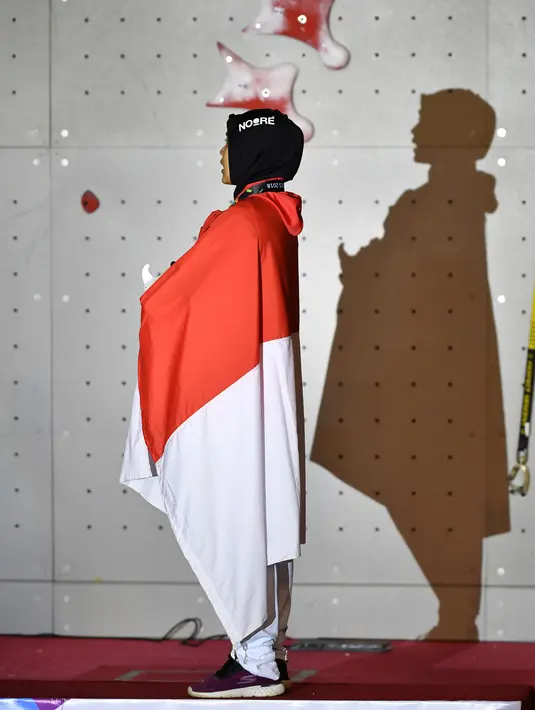Peraih medali emas Indonesia Susanti Rahayu Aries mendengarkan lagu kebangsaan Indonesia Raya pada upacara penyerahan medali olahraga panjat tebing wanita Asian Games 2018 di Palembang (23/8). (AFP PHOTO / Adek Berry)