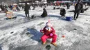 Seorang anak memancing ikan trout di sungai yang membeku di Hwacheon, Korea Selatan (6/1). Dalam lombo ini, peserta memancing ikan melalui lubang yang dibuat dipermukaan sungai yang membeku. (AP Photo/Ahn Young-joon)