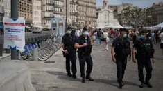 Polisi anti huru-hara Prancis mengamati warga yang mengenakan masker di Marseille, Selasa (18/8/2020). Pemerintah Prancis mengirim polisi anti huru hara ke wilayah Marseille untuk membantu menegakkan peraturan penggunaan masker saat negara itu mencatat lonjakan kasus COVID-19. (AP Photo/Daniel Cole)