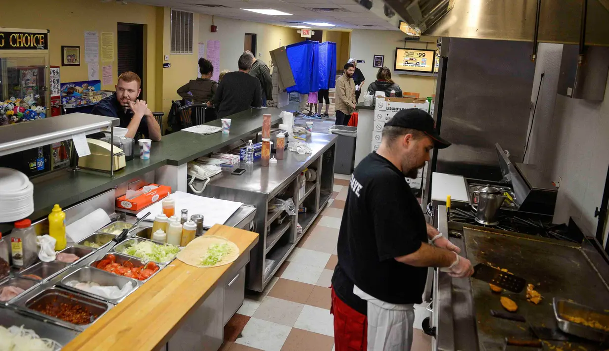 Pemilih (belakang) menggunakan hak pilihnya di dalam sebuah restoran, Lee Hoagie House, yang dijadikan lokasi tempat pemungutan suara (TPS) pemilihan presiden Amerika Serikat (Pilpres AS) di Chicago, Illinois, Selasa (8/11). (REUTERS/Jim Young)
