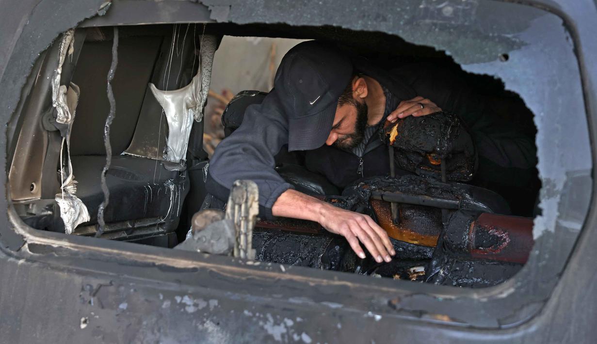 Seorang pria Palestina memeriksa mobil yang rusak akibat serangan oleh pemukim Israel di desa Jabaa dekat Bethlehem, di Tepi Barat yang diduduki, pada Selasa 18 November 2025. Kekerasan yang dilakukan pemukim Israel meningkat tajam dalam beberapa pekan terakhir di seluruh Tepi Barat. (AHMAD GHARABLI/AFP)