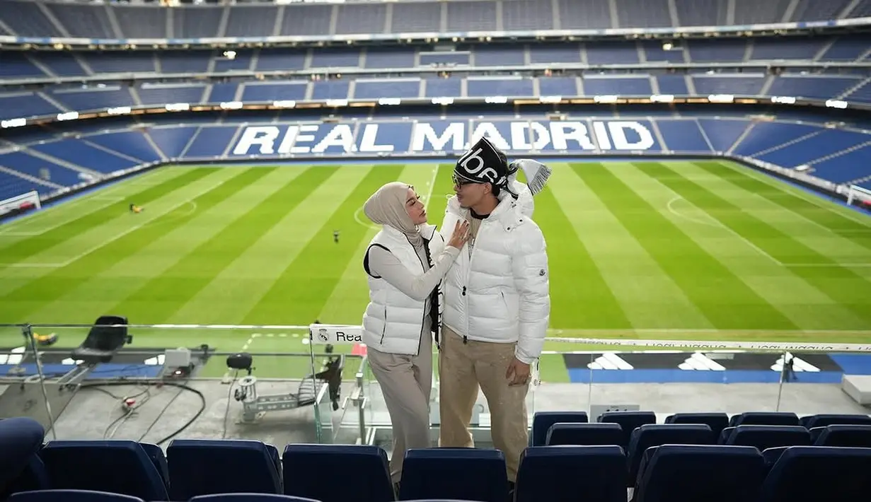 Pasangan Atta Halilintar dan Aurel Hermansyah banyak menunjukkan gaya kompak salah satunya saat berkunjung ke Estadio Santiago Bernabéu. Keduanya tampil serasi mengenakan puffer vest dan jaket warna putih dengan gaya khas masing-masing [@aurelie.hermansyah].