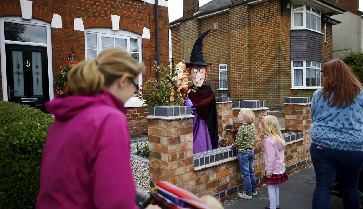 Anak-anak melihat orang-orangan sawah dari karakter "Room on a Broom" saat Festival Scarecrow di Heather, Inggris, 28 Juli 2015. Festival sejak 1999 ini selalu menarik perhatian wisatawan mancanegera  untuk berdatangan ke Inggris. (REUTERS/Darren Staples)