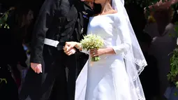 Pangeran Harry mencium istrinya, Meghan Markle saat mereka berangkat dari Pintu Barat St George's Chapel, Kastil Windsor, Inggris, Sabtu (19/5). Pangeran Harry dan Meghan Markle telah resmi menikah. (Ben STANSALL/POOL/AFP)