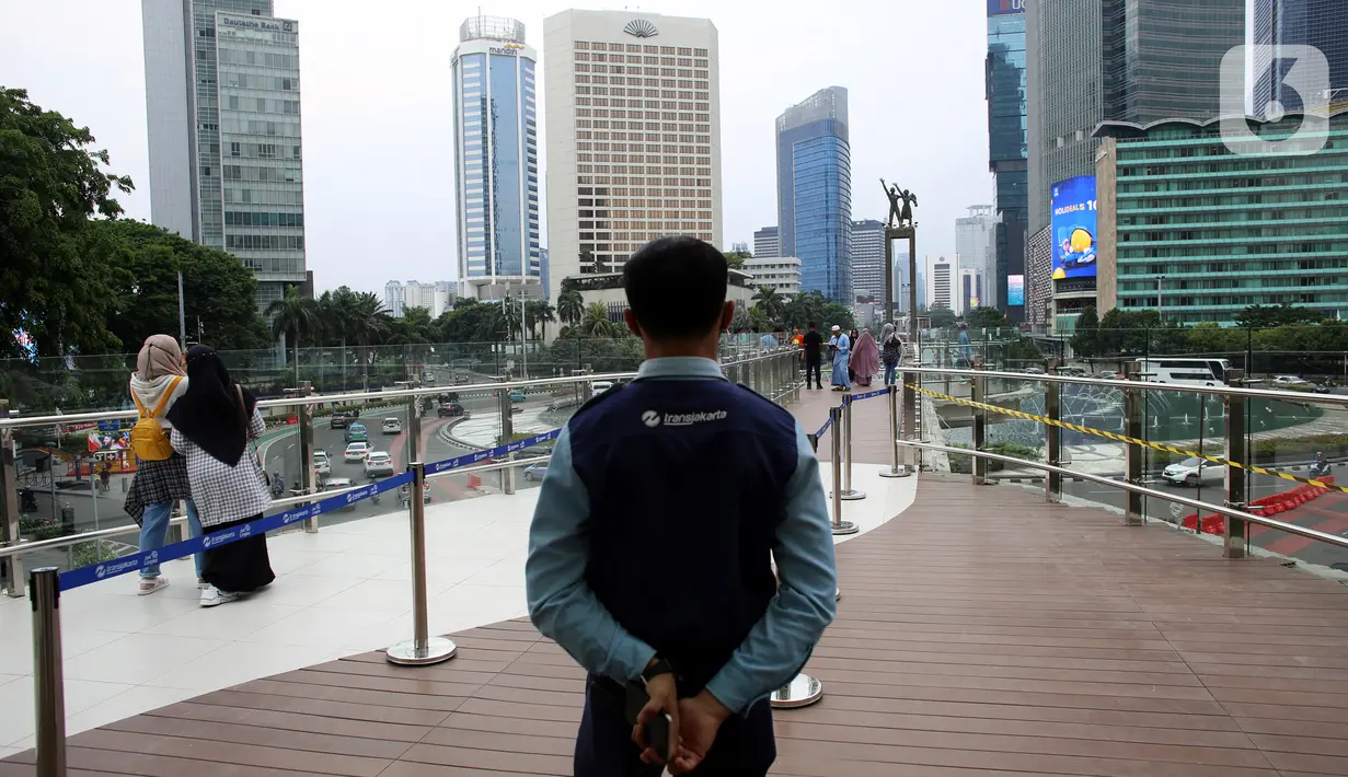 Petugas berjaga saat warga menikmati pemandangan dari anjungan Halte Transjakarta Bundaran HI saat uji coba anjungan itu di kawasan Bundaran Hotel Indonesia, Jakarta, Senin (10/10/2022). Lokasi tersebut jadi spot foto baru dengan latar belakang Patung Selamat Datang dan air mancur Bundaran HI. (Liputan6.com/Johan Tallo)