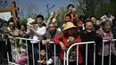 Para penduduk menyaksikan perlombaan lari half marathon yang diikuti oleh robot humanoid di Beijing, China, Sabtu (19/04/2025). (AFP/Pedro Pardo)