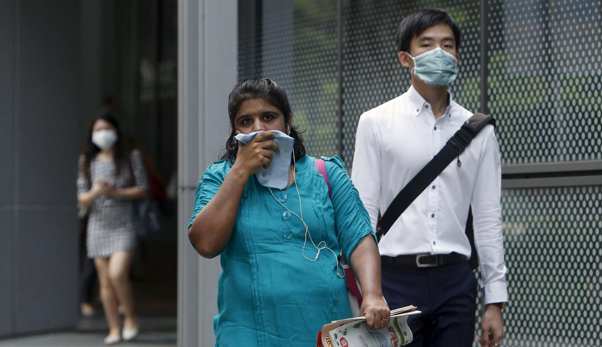 Pekerja memakai masker saat berjalan di pusat bisnis, Singapura (25/9/2015). Menurut Badan Lingkungan Nasional Singapura kabut Polutan Standar Indeks (PSI) mencapai tinggi 341 pada hari Jumat. (REUTERS/Edgar Su)
