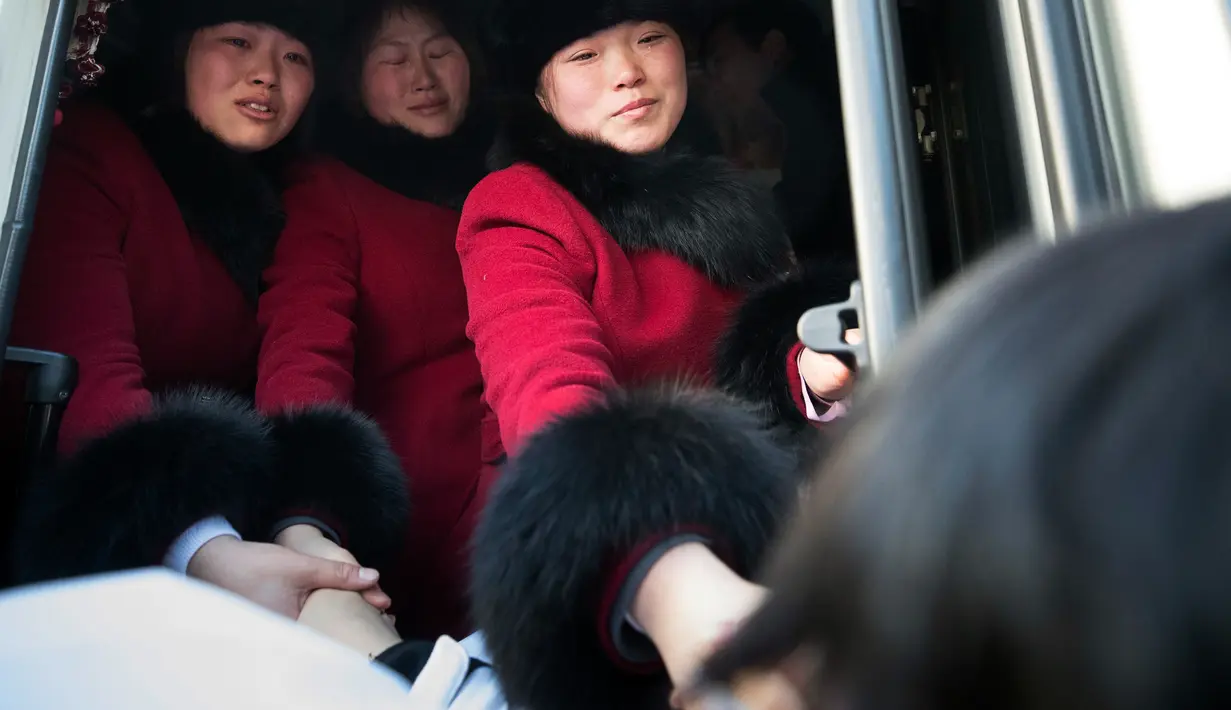 Para pemain tim hoki wanita Korea Utara meraih tangan rekan mereka asal Korea Selatan saat akan kembali ke negaranya usai mengikuti Olimpiade Pyeongchang di Olympic Village, Gangneung, Korea Selatan, Senin (26/2). (Yun Dong-jin/Yonhap via AP)