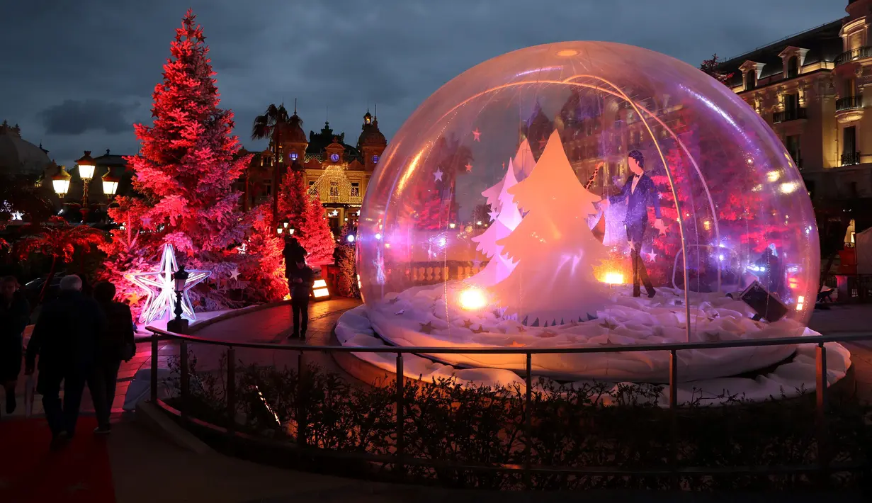 Orang-orang mengunjungi bola kaca raksasa dan dekorasi untuk menyambut Natal yang menghiasi depan Kasino Monte-Carlo di Monako pada 7 Desember 2018. (Photo by VALERY HACHE / AFP)