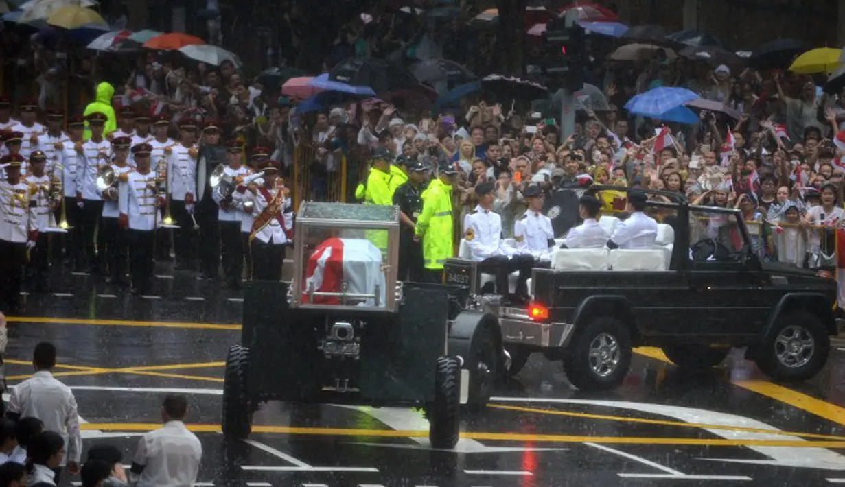 Hujan tak menyurutkan semangat warga Singapura untuk mengiringi perjalanan jenazah Lee Kuan Yew ke Universitas Nasional Singapura, Singapura, Minggu (29/3/2015). Di universitas tersebut jenazah Lee Kuan Yew akan dikremasi.(AFP PHOTO / MOHD FYROL)