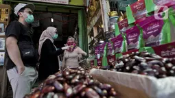 Pedagang kurma melayani pembeli di Pasar Tanah Abang, Jakarta, Rabu (22/4/2020). Pandemi COVID-19 membuat lesu penjualan kurma, keuntungan pedagang menurun hingga 80 persen lebih padahal pada tahun sebelumnya menjelang Ramadan biasanya ramai pembeli. (Liputan6.com/Johan Tallo)