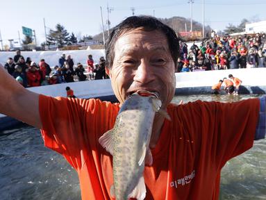 Seorang peserta berpose dengan ikan dengan saat acara Festival Es di sungai Hwacheon yang membeku di Korea Selatan, Sabtu (14/1). (AP Photo/Ahn Young-joon)