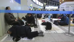 Seorang pria tidur ketika dia menunggu untuk membeli tiket kereta api untuk mudik ke kota asalnya selama liburan Tahun Baru Imlek, di Stasiun Kereta Api Seoul di Seoul, Korea Selatan, Selasa (7/1/2020). Tahun Baru Imlek jatuh pada 25 Januari tahun ini. (AP Photo/Ahn Young-joon)