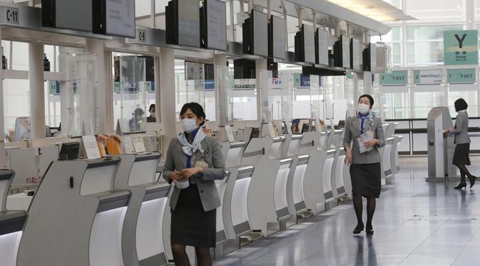 Ground staff bekerja di lobi keberangkatan Bandara Internasional Haneda yang sepi di Tokyo, Senin (28/12/2020). Jepang untuk sementara waktu melarang semua pendatang asing yang bukan penduduk masuk sebagai bentuk antisipasi varian baru COVID-19 hingga akhir Januari 2021. (AP Photo/Koji Sasahara)