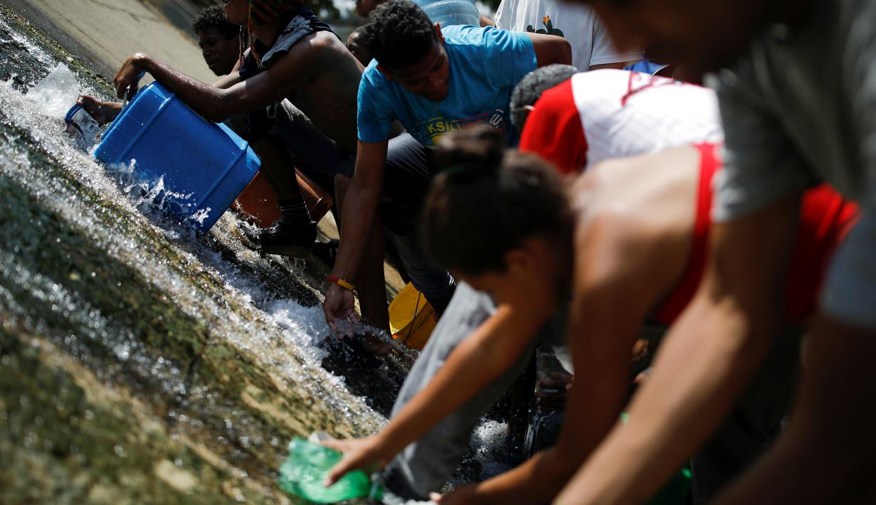 Orang-orang mengumpulkan air yang keluar melalui saluran pembuangan air limbah yang mengalir ke Sungai Guaire di Caracas, 11 Maret 2019. Pemadaman listrik selama berhari-hari di Venezuela berdampak terhadap krisis air. (REUTERS/Carlos Garcia Rawlins)