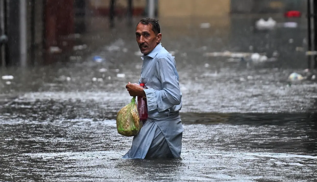 Seorang pria menyeberangi jalan yang tergenang air saat hujan monsun lebat di Rawalpindi, Pakistan, pada 17 Juli 2025. (Aamir Qureshi/AFP)