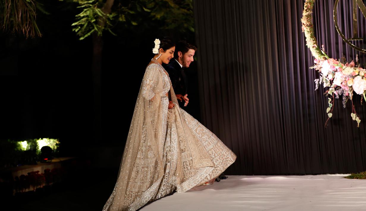Aktris Bollywood Priyanka Chopra dan musisi AS Nick Jonas berjalan saat resepsi pernikahan mereka di New Delhi, India, Selasa (4/12). Priyanka Chopra dan Nick Jonas menikah dalam dua upacara yang berbeda. (AP Photo/Altaf Qadri)