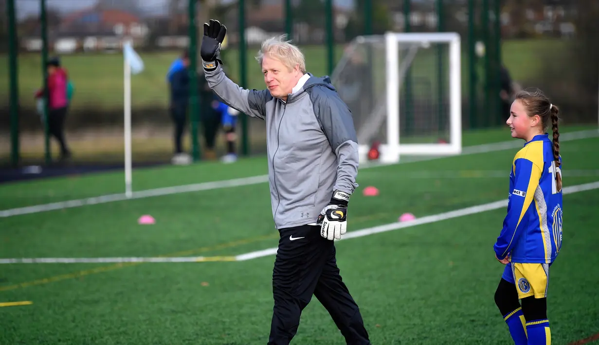 PM Inggris Boris Johnson memberi isyarat saat menghadiri pertandingan sepak bola putri junior antara Hazel Grove United JFC dan Poynton di Cheadle Hulme, Inggris, Sabtu (7/12/2019). Aksi itu dalam rangka kampanye jelang pemilu Inggris pada 12 Desember 2019. (Toby Melville/Pool Photo via AP)