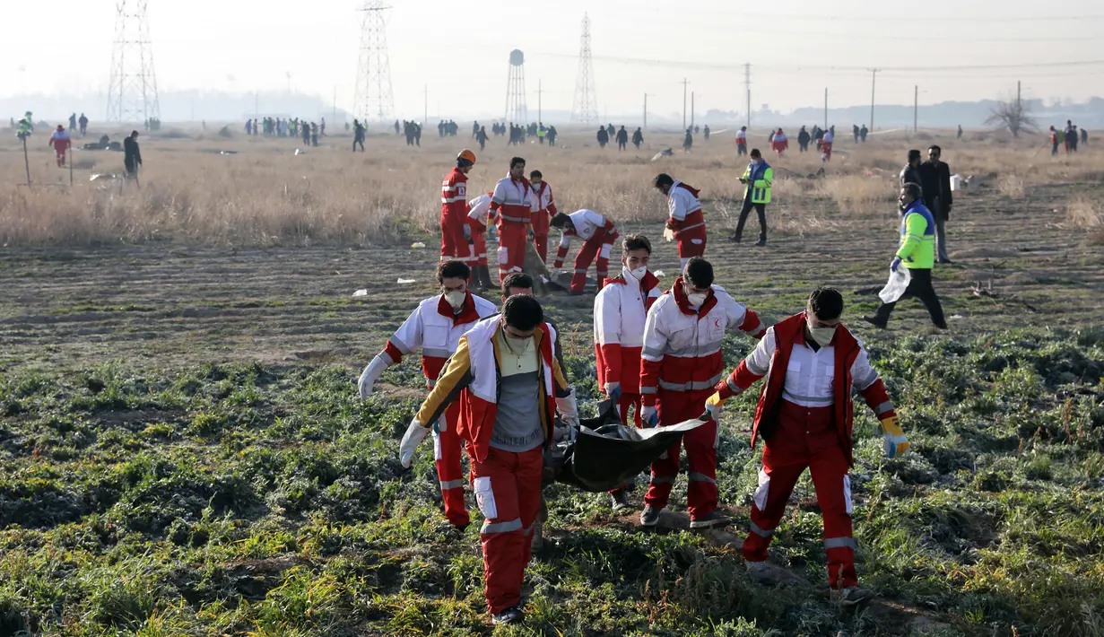 Tim penyelamat membawa jasad korban jatuhnya pesawat Boeing 737-800 di Shahedshahr, Iran, Rabu (8/1/2020). Korban tewas terdiri dari 82 warga Iran, 63 warga Kanada, 11 warga Ukraina, 10 warga Swedia, 4 warga Afghanistan, 3 warga Jerman, dan 3 warga Britania Raya. (AP Photo/Ebrahim Noroozi)