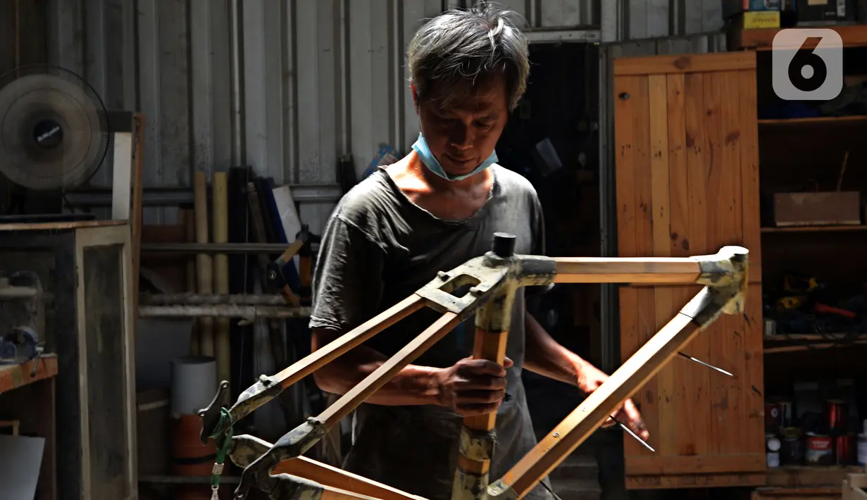 Pekerja menyelesaikan pembuatan sepeda yang terbuat dari bambu di Workshop Arana Bike, Gunung Putri, Kabupaten Bogor, Jawa Barat, Selasa (15/3/2022). Tipe Komodo dan Minivelo dijual dengan harga Rp 5 juta per rangkanya. (merdeka.com/Imam Buhori)
