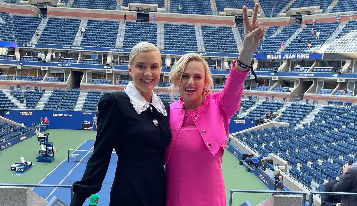 <p>Rebel Wilson tampil dengan dress dan jaket crop top pink. Ia juga memakai heels nude transparan di US Open 2022 yang digelar di USTA Billue Jean King Natioan Tennis Center di New York City. (Foto: Instagram @rebelwilson)</p>