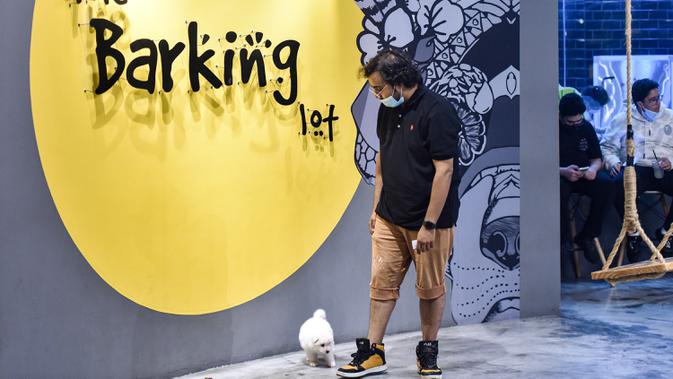 Seorang pria berjalan di samping anjingnya di kafe 