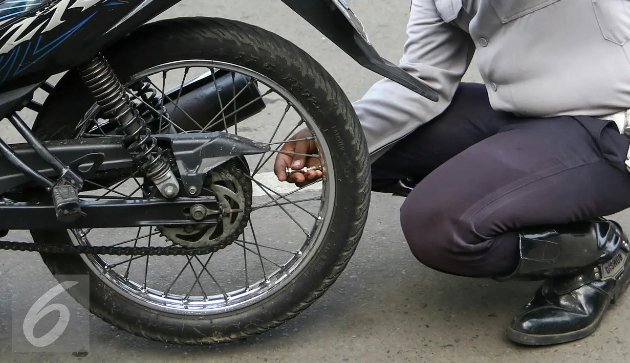 Petugas Dishub DKI Jakarta mengembosi motor yang nekat parkir liar di Jalan St.Senen, Jakarta Pusat, Selasa (29/3/2016). Kendaraan roda dua terparkir di bahu jalan ataupun trotoar langsung ditindak. (Liputan6.com/Yoppy Renato)
