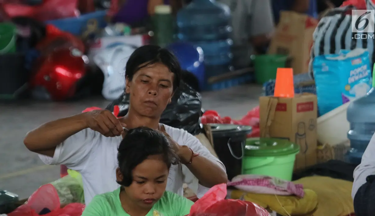 Seorang ibu dan anaknya beraktivitas di GOR Swecapura, Klungkung, Bali, Senin (27/11). Pada saat Gunung Agung ditetapkan status awas bulan September lalu, total pengungsi di Kabupaten Klungkung sempat mencapai 24 ribu jiwa. (Liputan6.com/Andi Jatmiko)