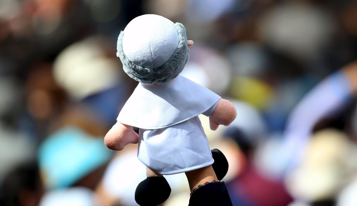 Seorang wanita memegang boneka menyambut kedatangan Paus Fransiskus di Universitas Katolik, Quito,Ekuador,(7/ 7/2015). Paus Fransiskus membahas tentang keadilan sosial dan keseimbangan sumber daya bumi. (REUTERS/Alessandro Bianchi)