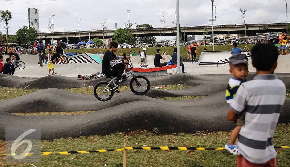 Seorang ayah yang menggendong anak menonton aksi pesepeda BMX Taman Kalijodo, Jakarta, Minggu (15/01). Sejak skate park dan lintasan sepeda BMX dibuka untuk umum, taman tersebut tidak pernah sepi pengunjung. (Liputan6.com/Fery Pradolo)