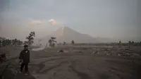 Seorang pria berdiri di depan Gunung Semeru menyusul letusan gunung berapi di desa Kajar Kuning di Lumajang (5/12/2022). Gunung Semeru meletus pada tanggal 4 Desember memuntahkan awan abu panas setinggi satu mil dan sungai lava di sisinya sambil memicu evakuasi hampir 2.000 orang tepat satu tahun setelah letusan besar terakhirnya menewaskan puluhan orang. (AFP/Juni Kriswanto)
