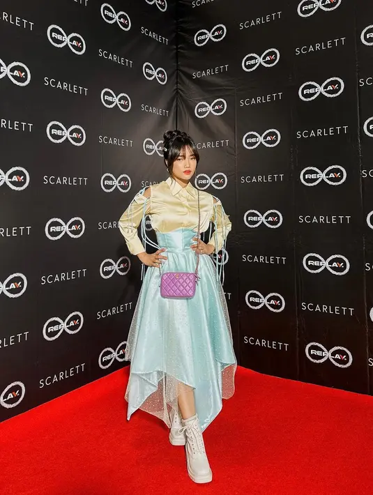 Fuji bak peri dengan outfit dua warna. Atasan berwarna kuning, lengan panjang dengan cut out manis di bagian ujung bahu, dipadukan dengan midi skirt yang berujung asimetris berwarna biru muda, sama-sama dari bahan satin. [Foto: Instagram/fuji_an]