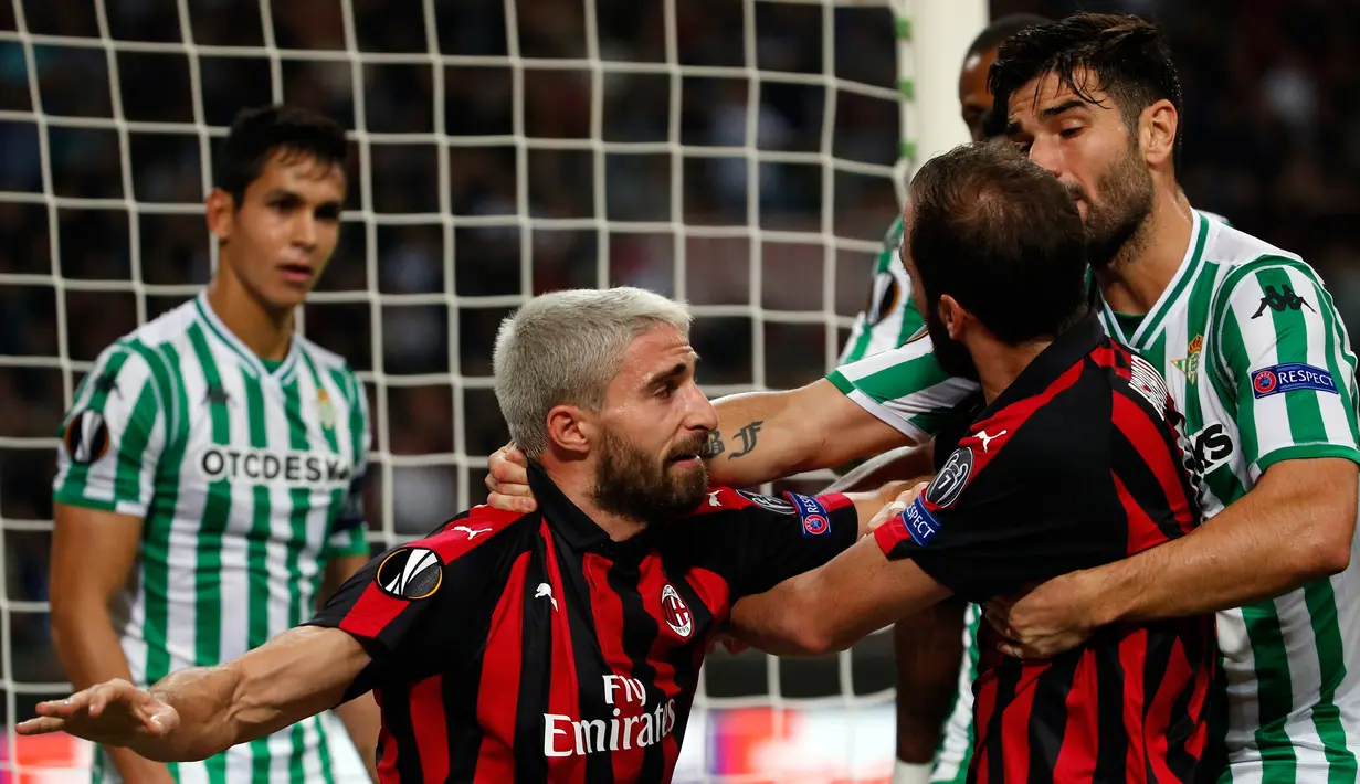 Pemain AC Milan, Fabio Borini (tengah) menahan Gonzalo Higuain saat mencoba mendekati pemain Real Betis Aissa Mandi (kiri) saat bertanding dalam Grup F Liga Europa di Stadion San Siro, Milan, Italia, Kamis (25/10). (AP Photo/Antonio Calanni)