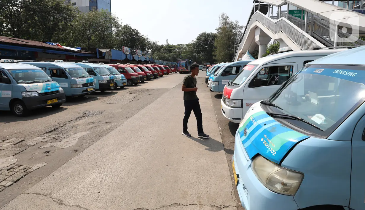 Seorang pria melintasi deretan angkutan kota (angkot) yang terparkir di Terminal Grogol, Jakarta, Sabtu (27/8/2022). Wakil Gubernur DKI Jakarta Ahmad Riza Patria berharap kenaikan tarif ojek online yang dimulai pada 29 Agustus mendatang bisa membuat banyak warga ibu kota beralih ke angkutan umum. (Liputan6.com/Angga Yuniar)