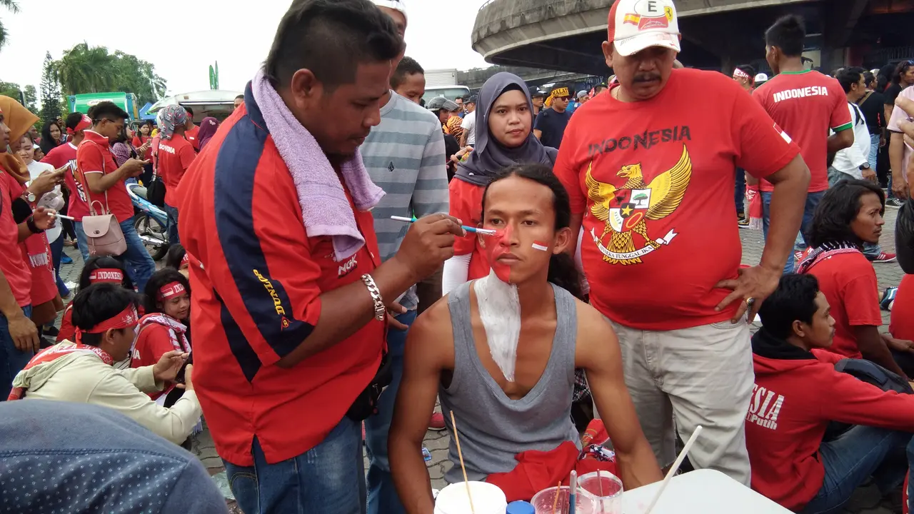 Pelukis wajah menggunakan duel Malaysia dan Timnas Indonesia U-22 di SEA Games sebagai ajang cari keuntungan. (Liputan6.com/Cakrayuri Nuralam)